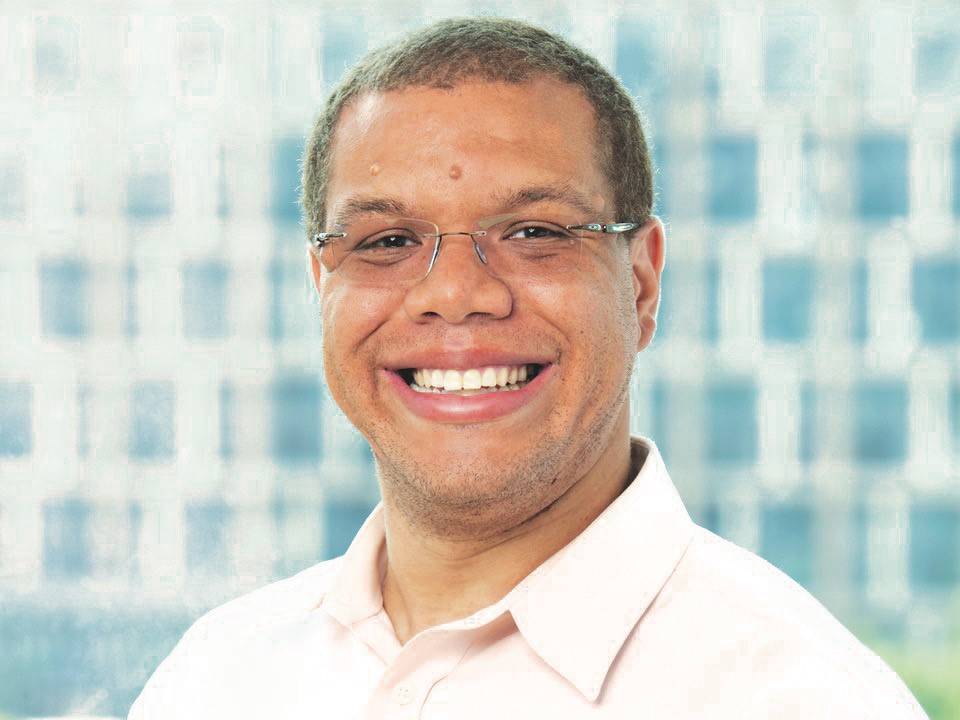 Michael Neal is smiling in this photo. He has short-cropped hair and is wearing glasses and a dress shirt.