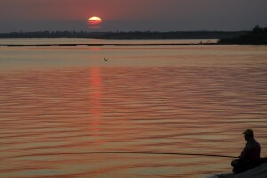 People fish at sunset in Buda, Romania, Thursday, Aug. 10, 2017. Romania's weather institute issued a new heatwave warning for the coming week across most of the country with temperatures expected to reach 39 degrees Centigrade (102.2 Fahrenheit). (AP Photo/Vadim Ghirda)