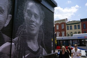 People down an alley past a mural depicting WNBA star Brittney Griner, top left, and other American hostages and wrongful detainees who are being held abroad, Wednesday, July 20, 2022, in the Georgetown neighborhood of Washington. (AP Photo/Patrick Semansky)