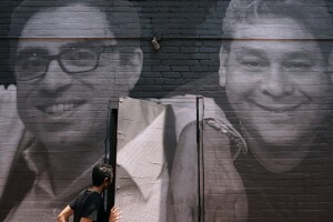 A woman steps through a door that is covered by a mural depicting American hostages and wrongful detainees who are being held abroad, Wednesday, July 20, 2022, in the Georgetown neighborhood of Washington. At left is Siamak Namazi, who has been in captivity in Iran since 2015. At right is Jose Angel Pereira, who has been imprisoned in Venezuela since 2017. (AP Photo/Patrick Semansky)