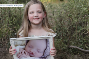 Emmalyn holding a picture of herself as a new born