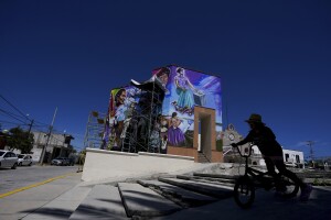 A pedestrian rides her bike in front of a mural painted by Mexican artist Jesus Rodriguez, in San Salvador, Mexico, Saturday, July 30, 2022. Artists helping to revive muralism or visual imagery to share messages of social and political importance, a movement that put Mexico at the vanguard of art a century ago. (AP Photo/Fernando Llano)