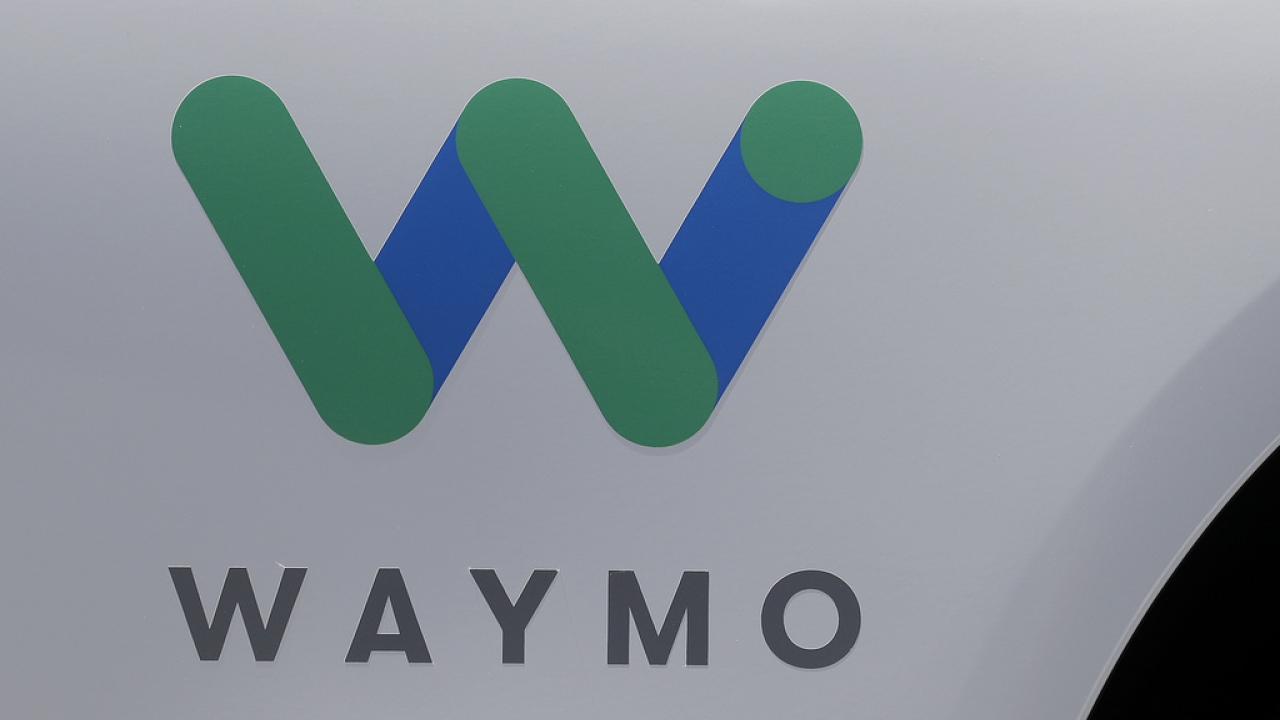 The Waymo logo appears on the door of a car