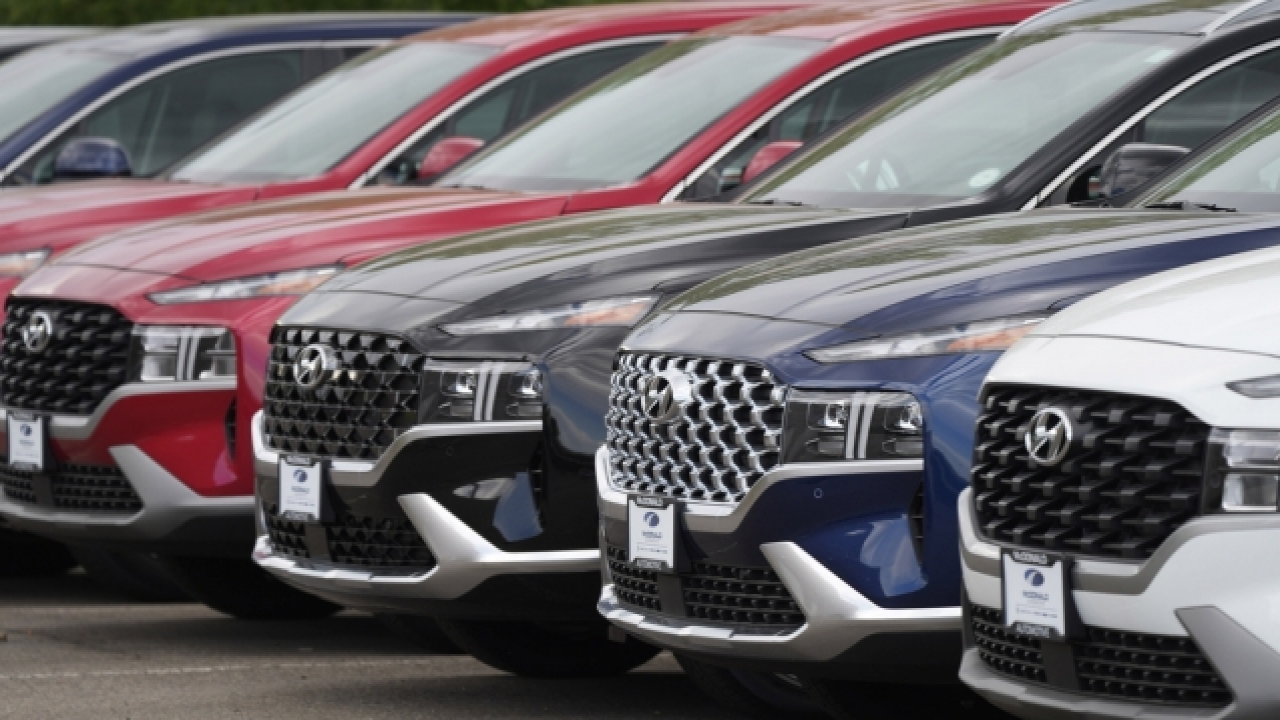 A line of 2022 Santa Fe SUV's sit outside a Hyundai dealership.