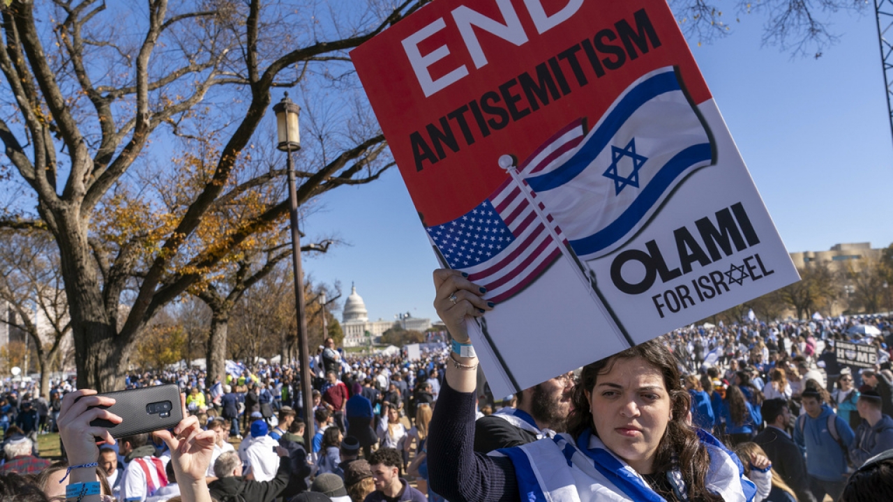 A woman holds a sign saying, "end antisemitism" while attending a march for Israel rally.