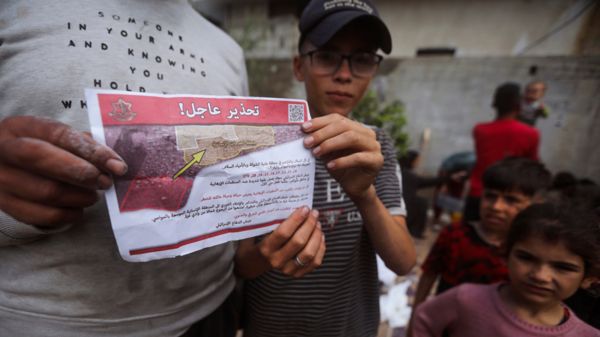Palestinians hold up a leaflets dropped by Israeli planes calling on them to evacuate.