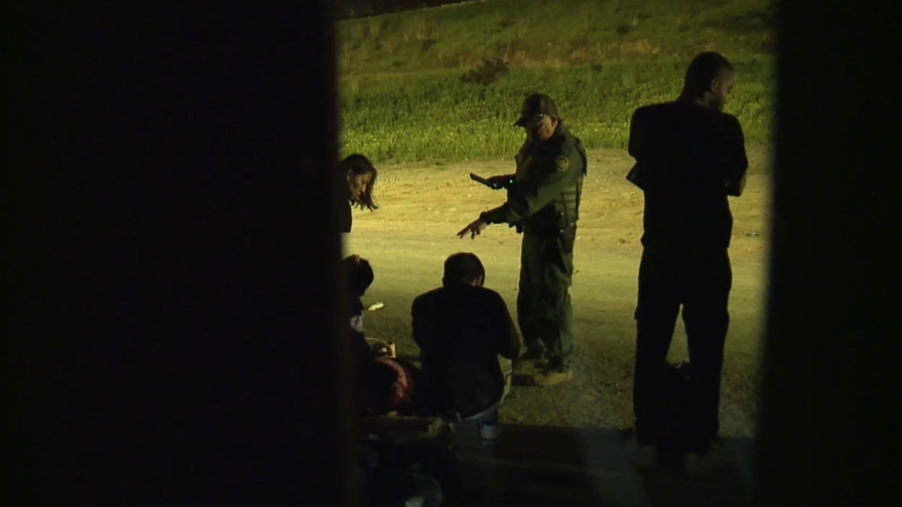 A U.S. Border Patrol agent speaks with migrants at the U.S.-Mexico border.