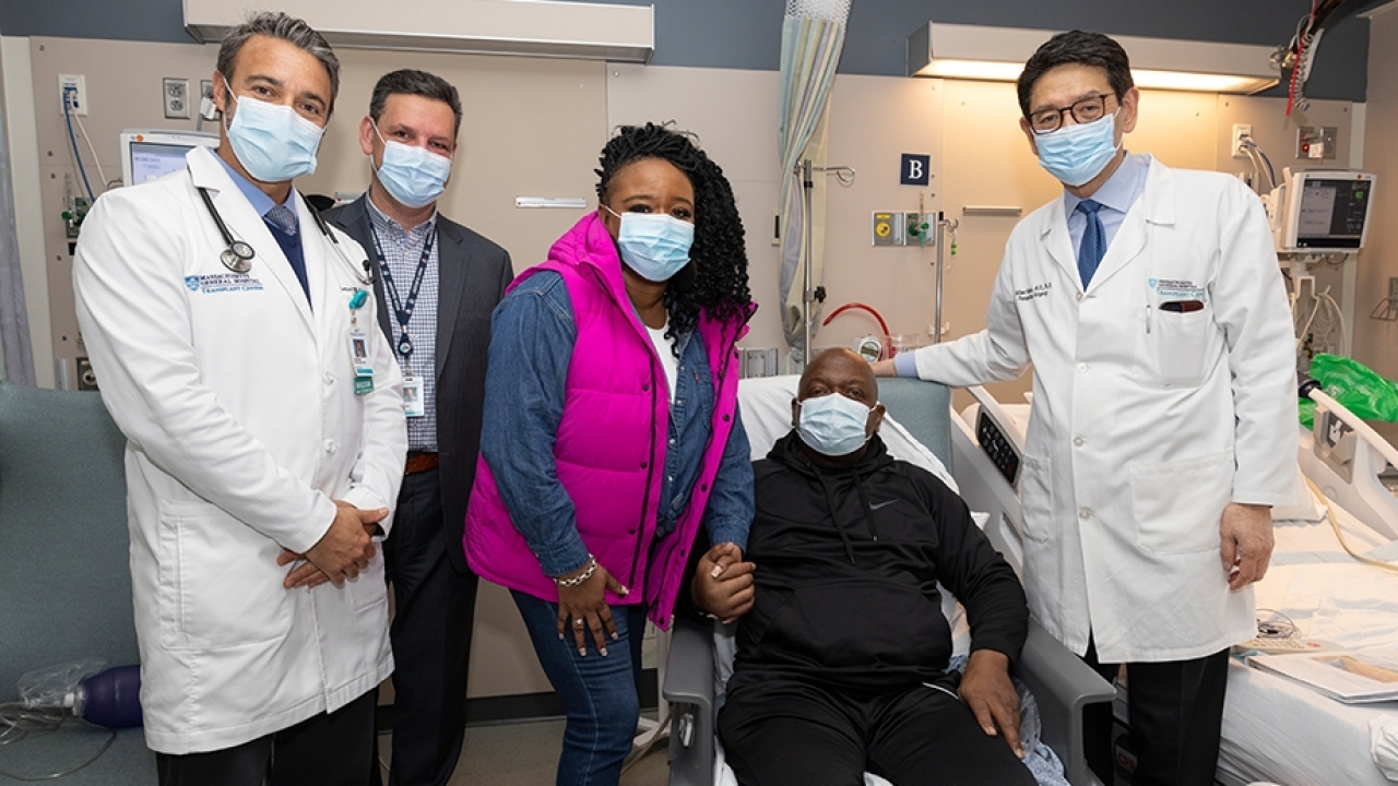 Rick Slayman sits in a chair in his hospital room surrounded by his medical team