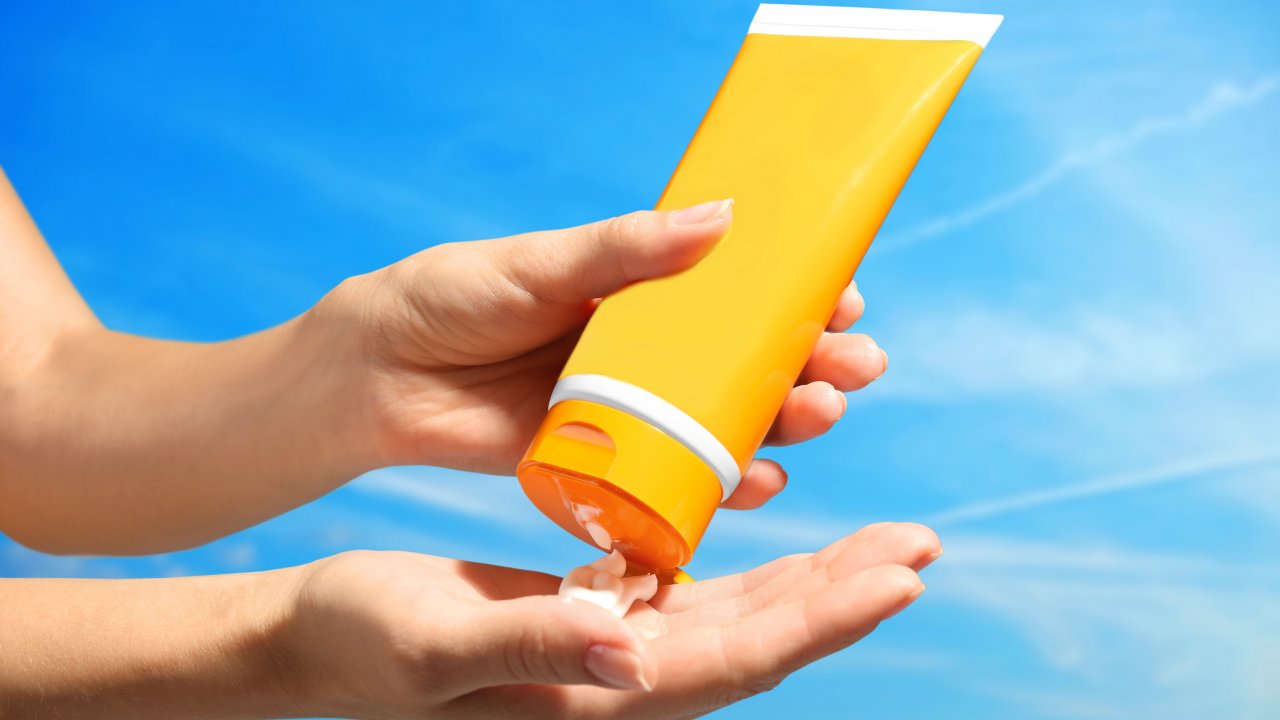Hands pour out some sunscreen from a bottle.