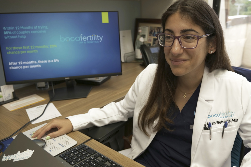 A doctor sits at her desk and works on her computer