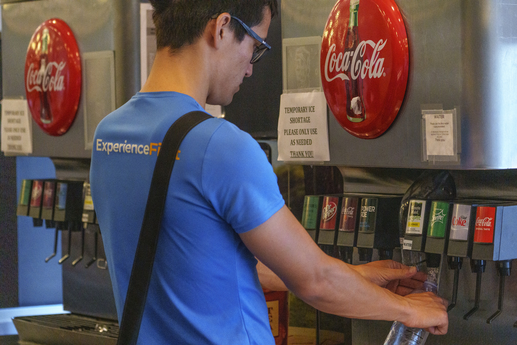 A restaurant patron refills a bottle with cold water at the beverage fountain.