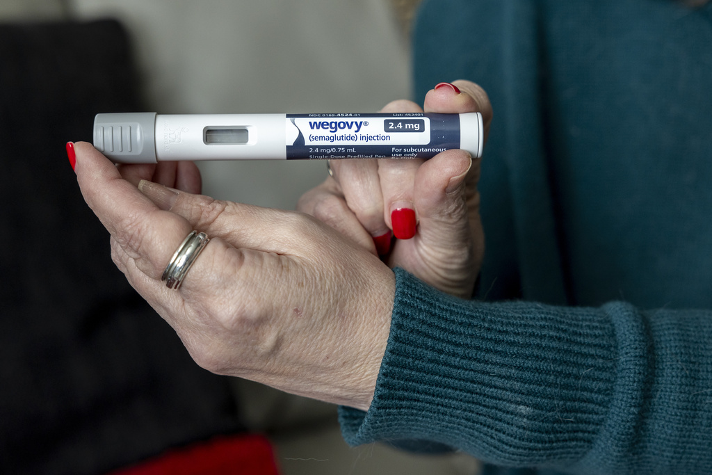 A woman holds up a dosage of Wegovy.