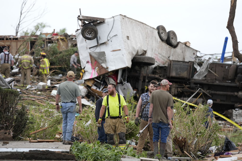 Workers search through the remains of tornado-damaged property.