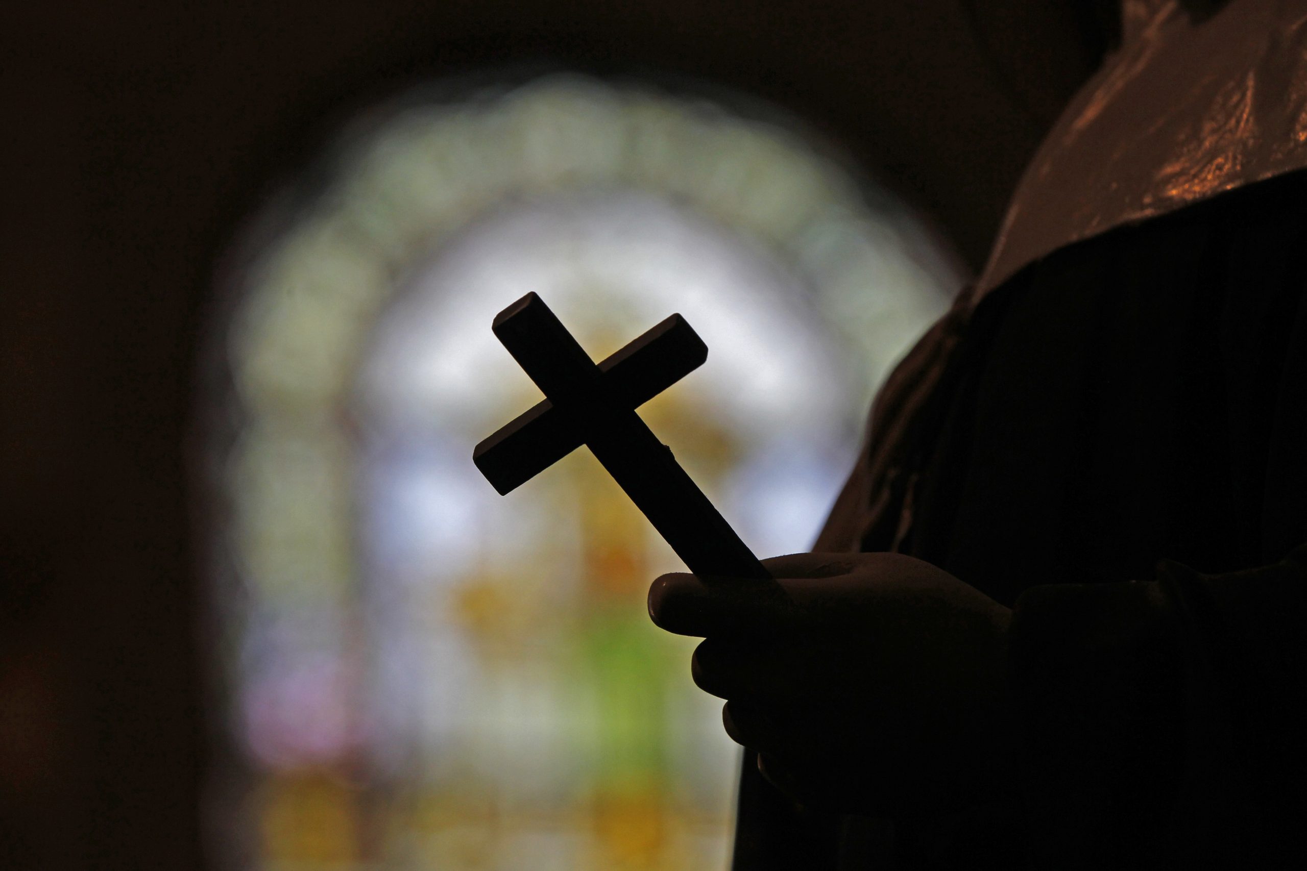 Silhouette of a crucifix and a stained glass window inside a Catholic Church in New Orleans.