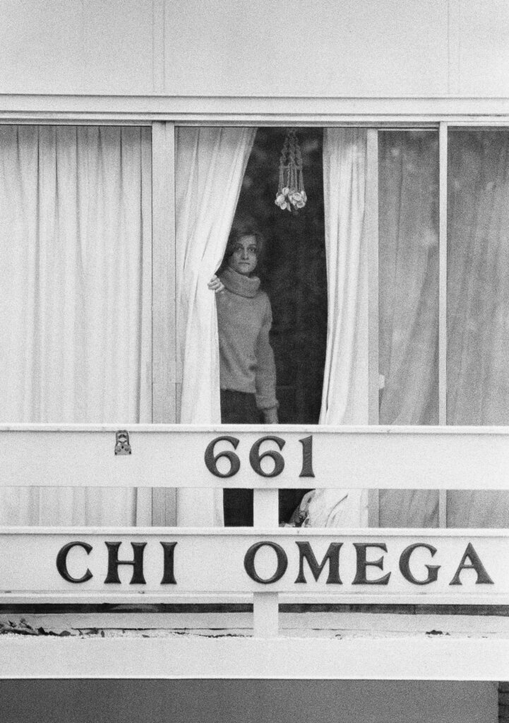 An unidentified woman peers through drapes on the second story balcony of the Chi Omega sorority house at Florida State University in 1978.