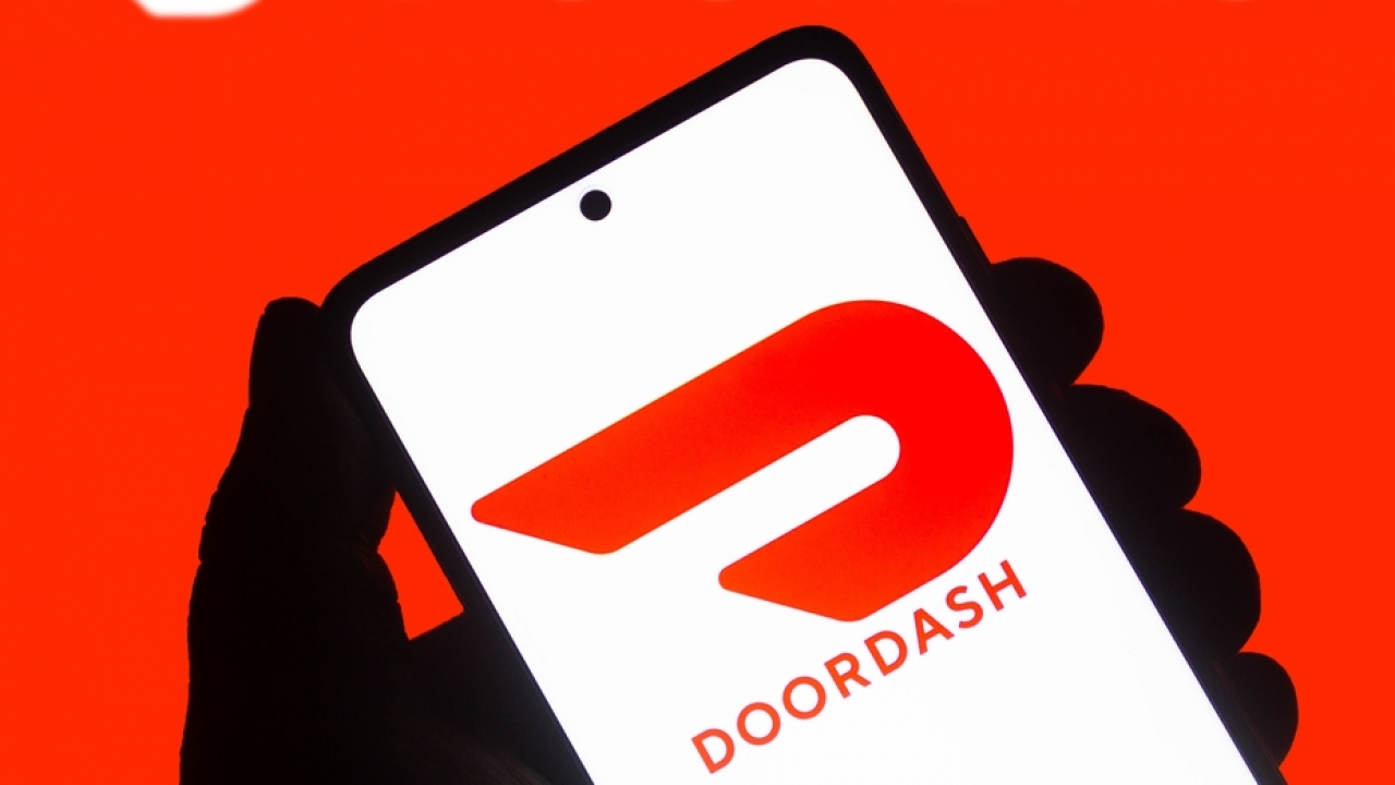 Hand holding phone with DoorDash logo white background