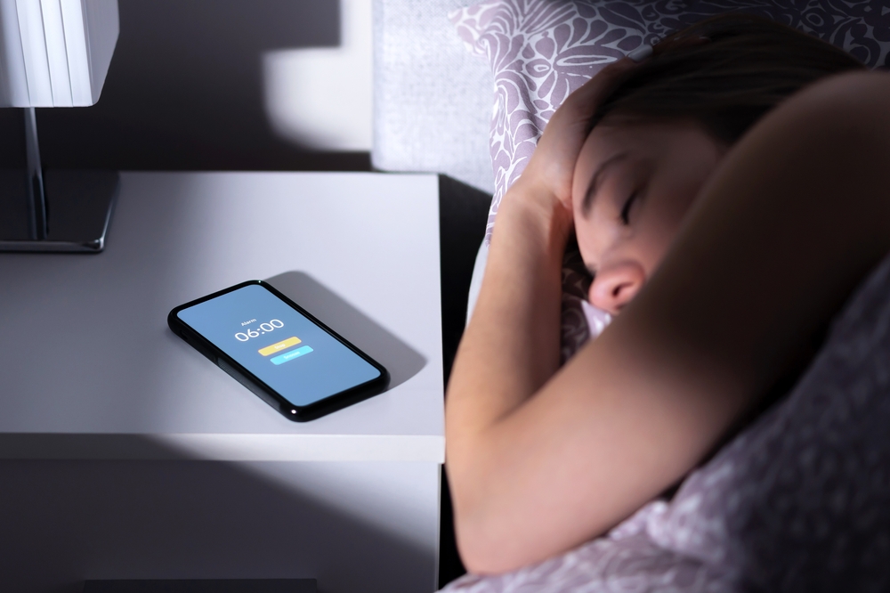 Phone alarm on a table next to a sleeping woman.