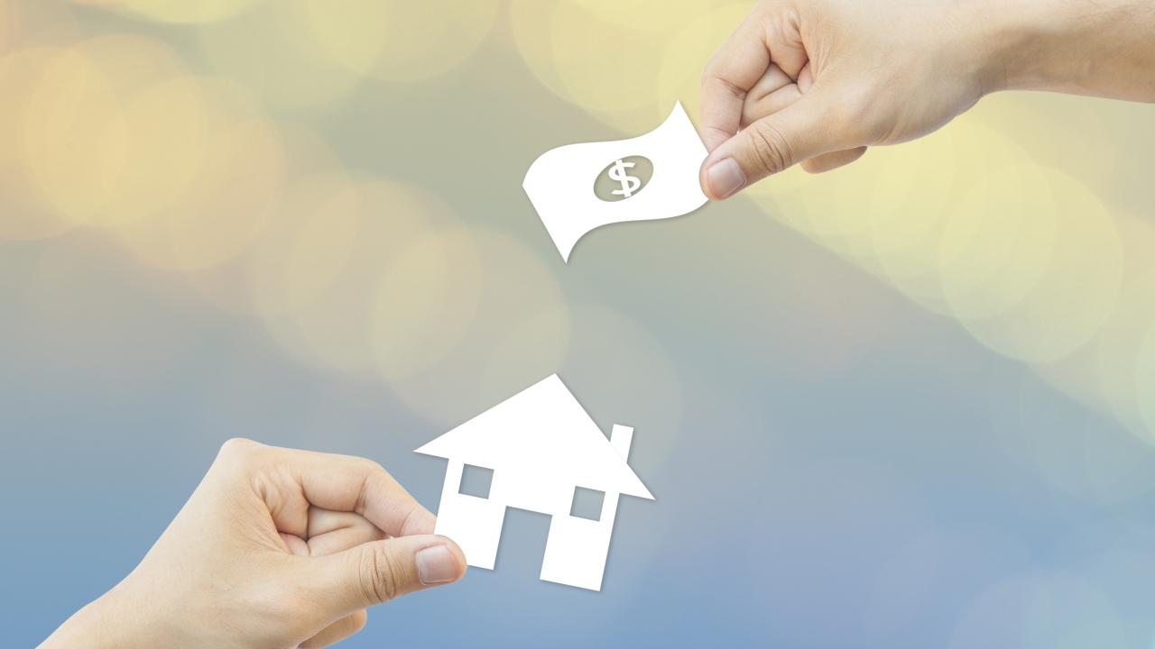 Business concept: hand holding house and money.