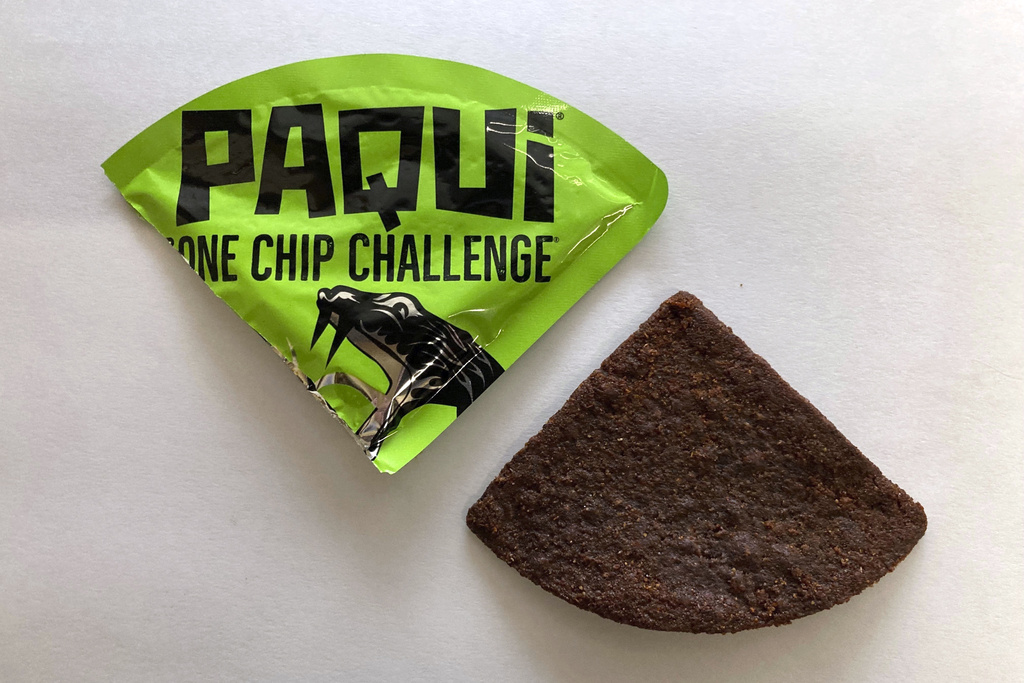 A Paqui One Chip Challenge chip is displayed next to its packaging.