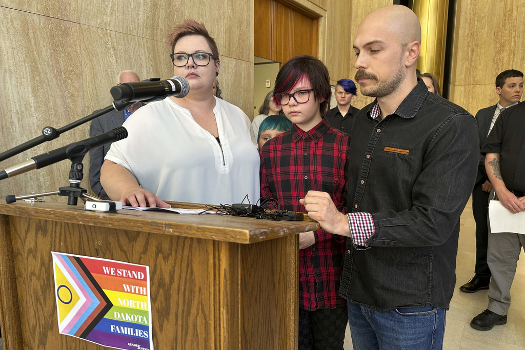 Parents Devon and Robert Dolney stand with their 12-year-old child, Tate. The Dolneys are plaintiffs in the lawsuit seeking to overturn North Dakota's law banning gender-affirming care for children.