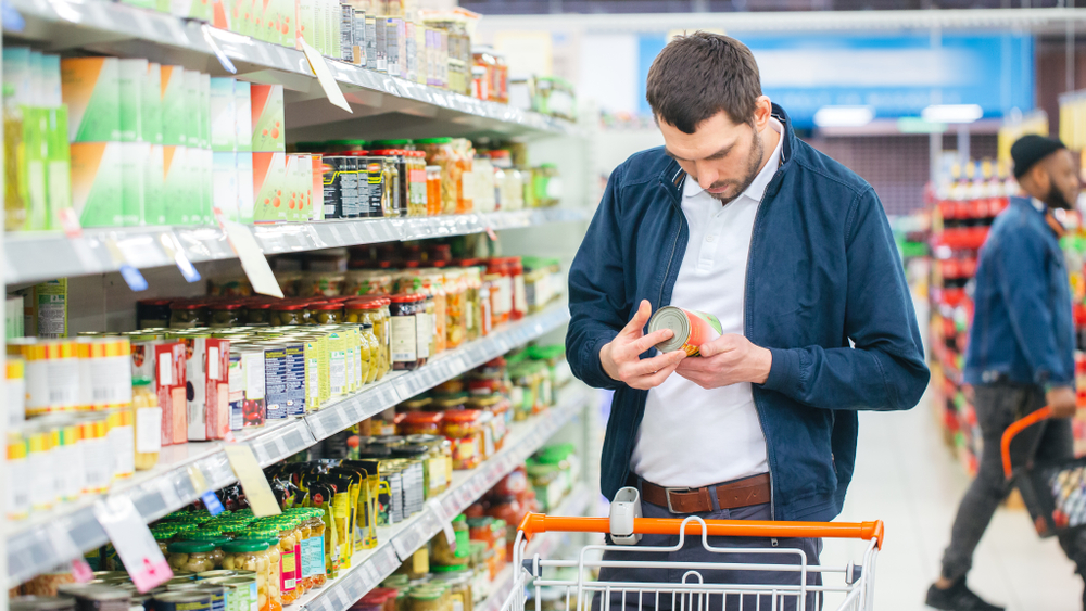 Shopper looking at a nutrition label in a grocery store.