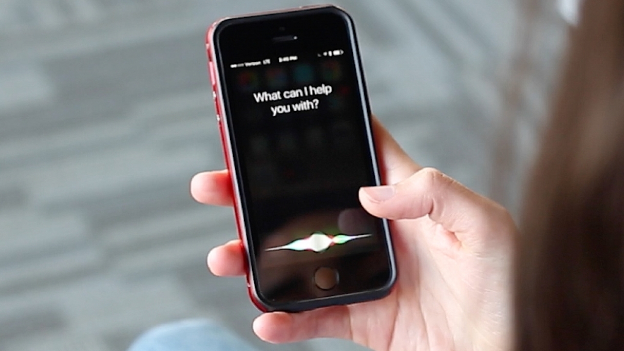 A woman asks Siri a question.