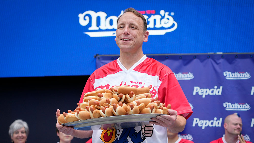 Competitive eater Joey Chestnut holds a plate of hotdogs.