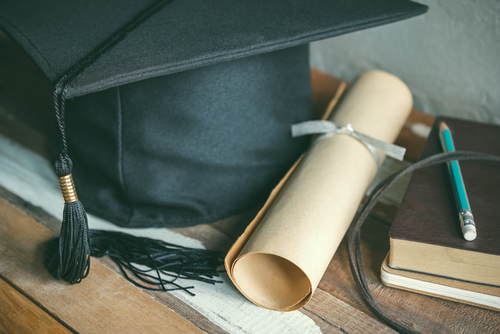 Stock image of a graduation cap and degree paper.
