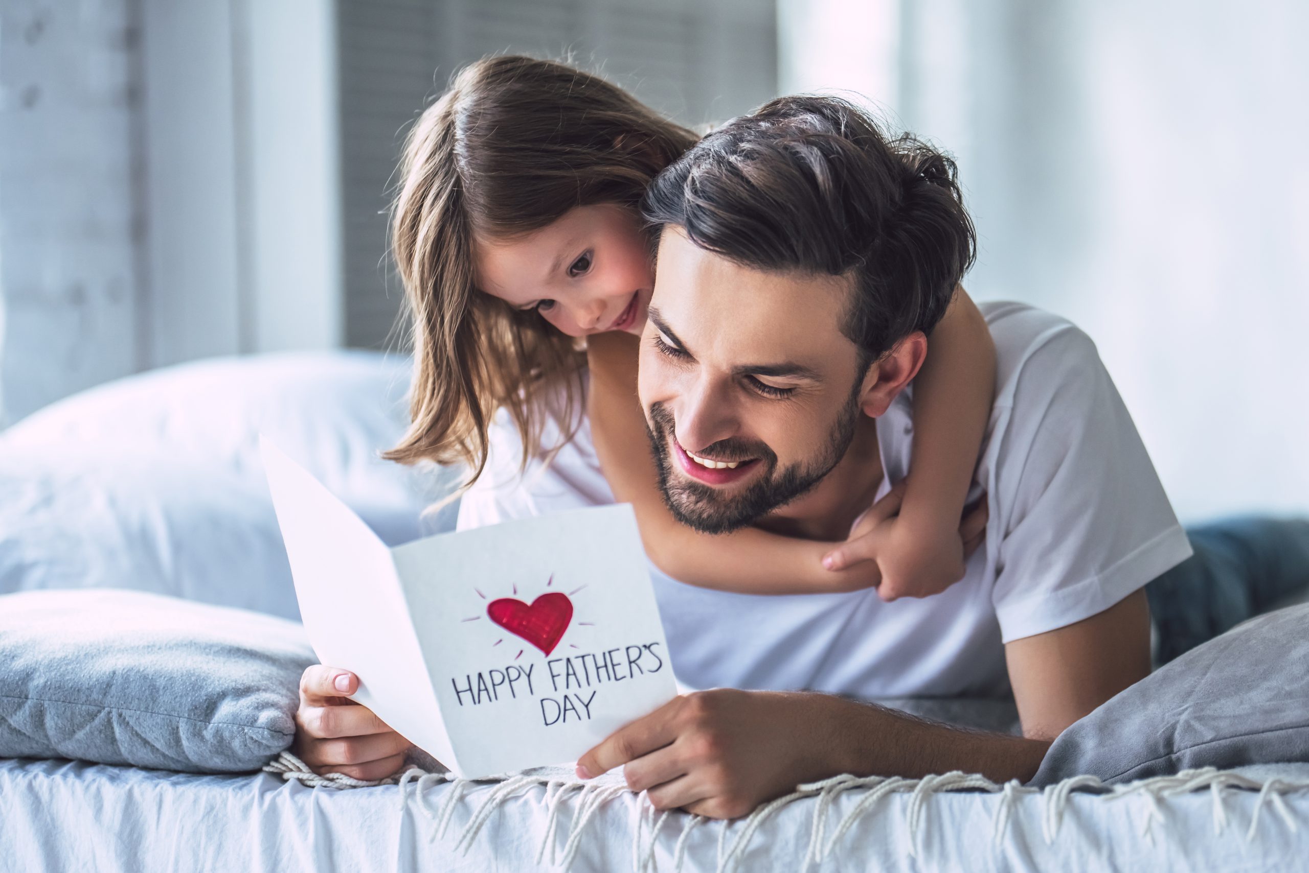 Child hugs dad reading Father's Day card.