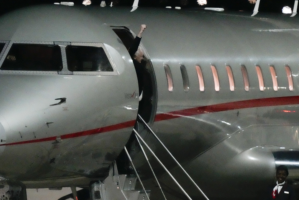 WikiLeaks founder Julian Assange disembarks from a plane in Australia with his fist raised in triumph