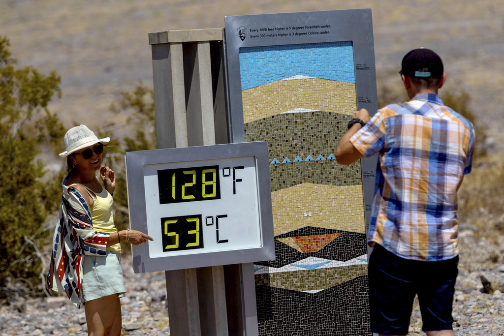 Tourists take photographs with the thermometer at the Furnace Creek Visitor Center during a dangerous heat wave in Death Valley, California