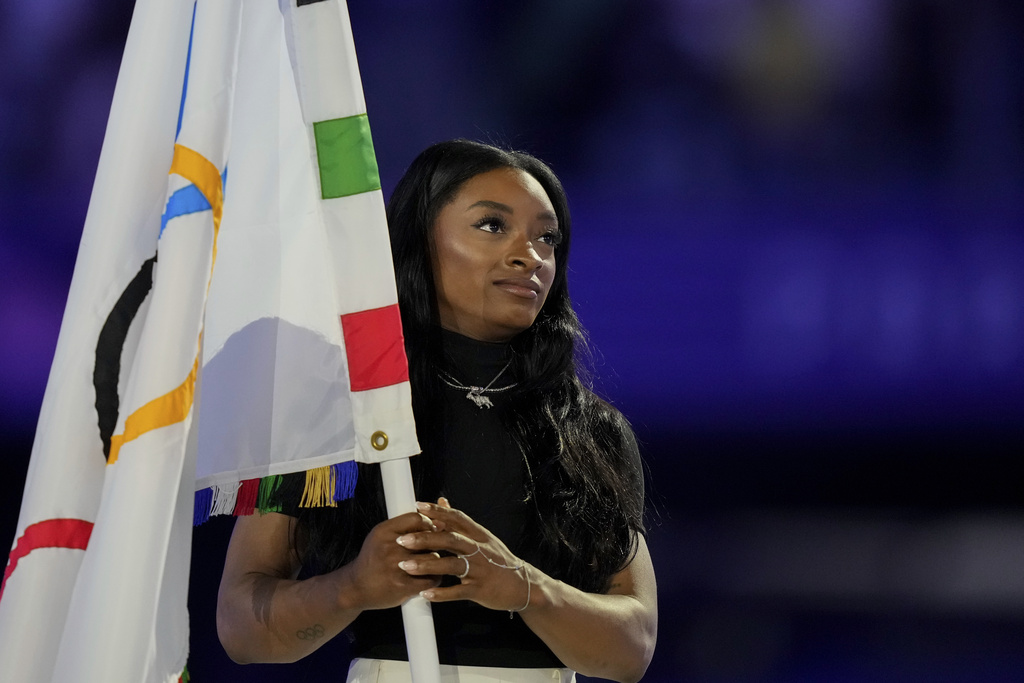 United States' gymnast Simone Biles holds the Olympic flag during the 2024 Summer Olympics closing ceremony.