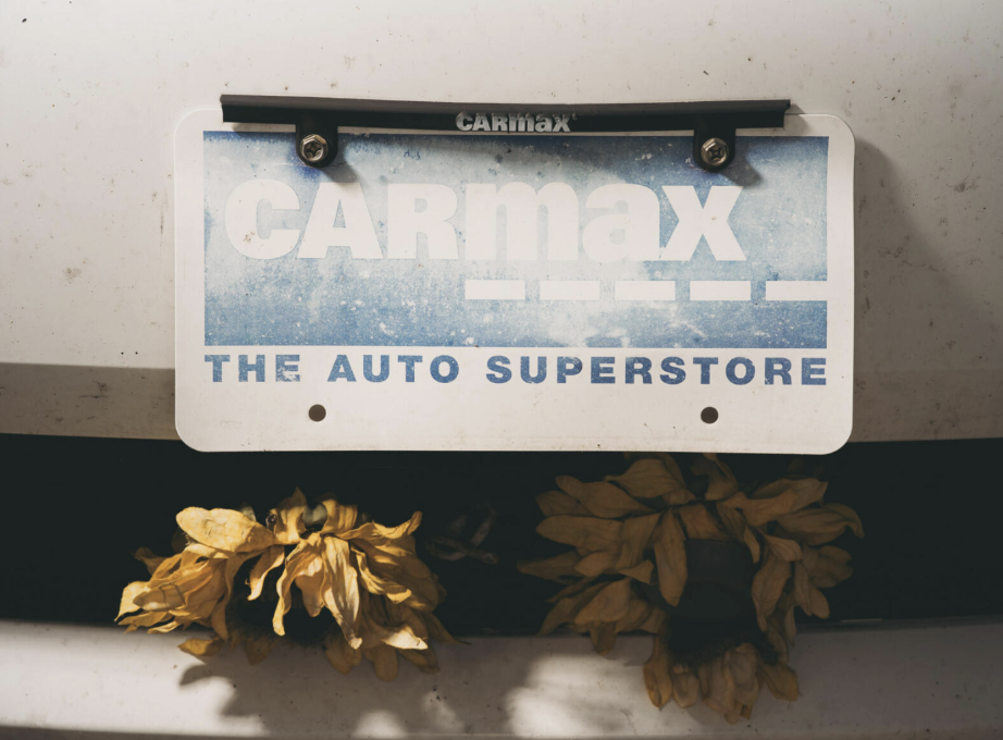 A faded Carmax plate on the front of Patterson’s car. 