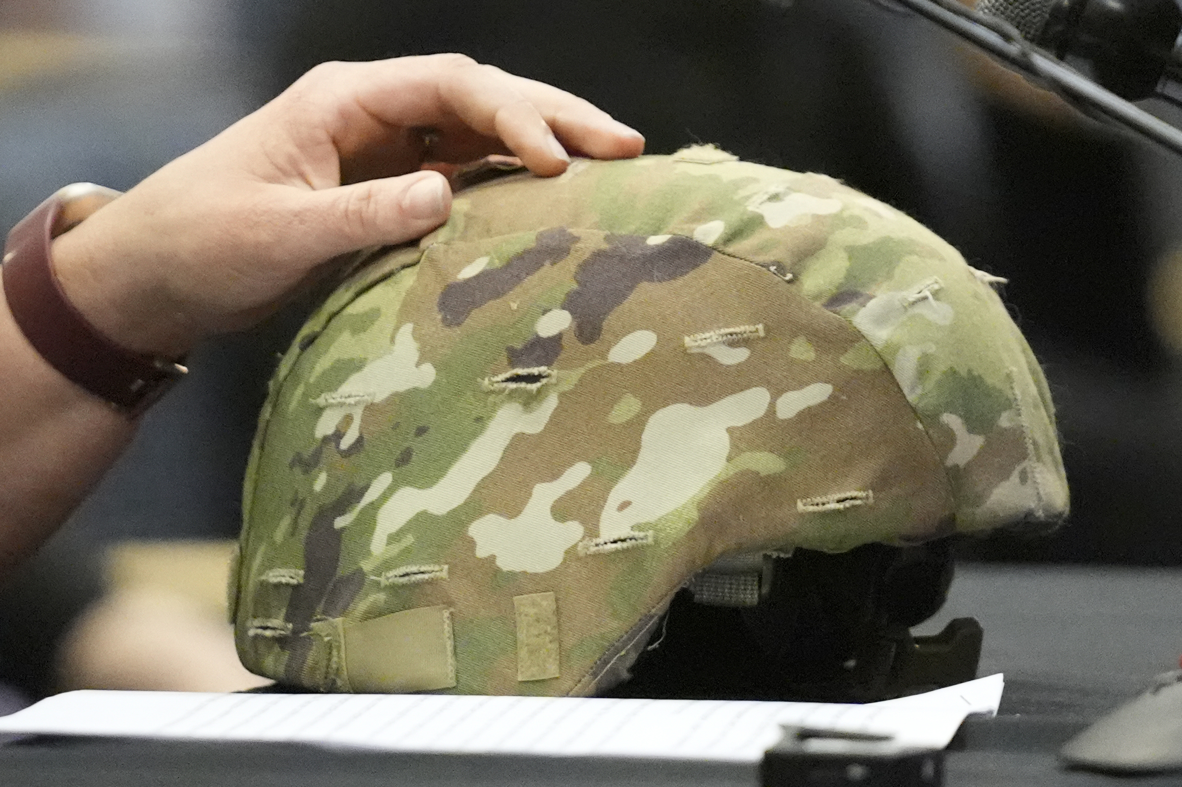 Nicole Herling, sister of shooter Robert Card, rests her hand on her brother's military helmet.