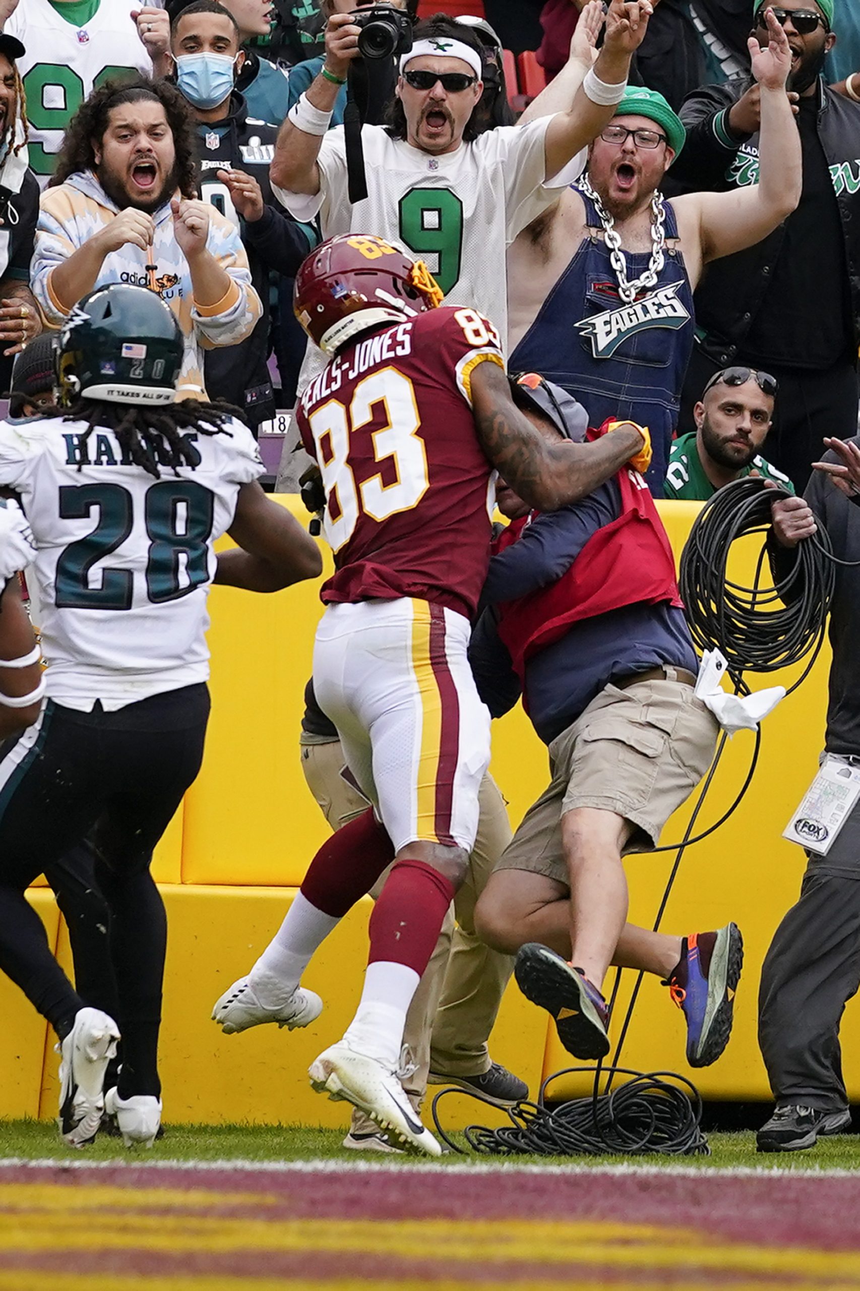 Washington Football Team tight end Ricky Seals-Jones (83) collides with a television cameraman during the first half of an NFL football game against the Philadelphia Eagles, Sunday, Jan. 2, 2022, in Landover, Md. Seals-Jones was carted off the field and was ruled out with an injury shortly after this play.