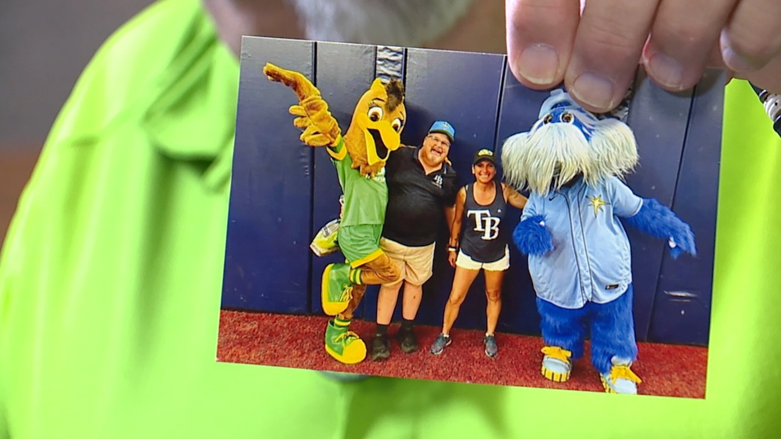 Tod Stutzman holds up a photo of him posing with sports mascots.