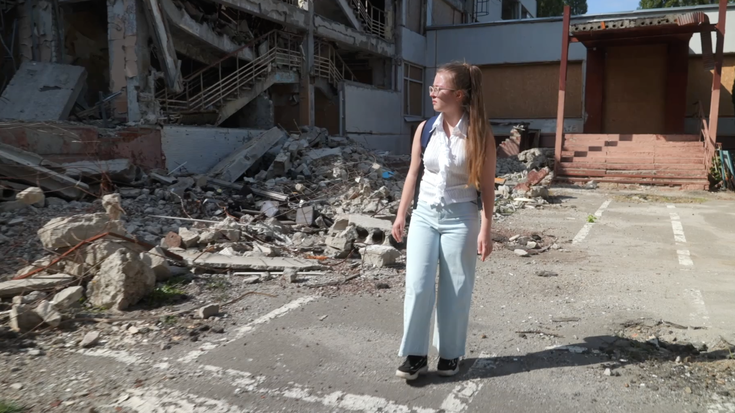 Yeva Yatsyk stands outside a school she attended that was destroyed in July 2022.
