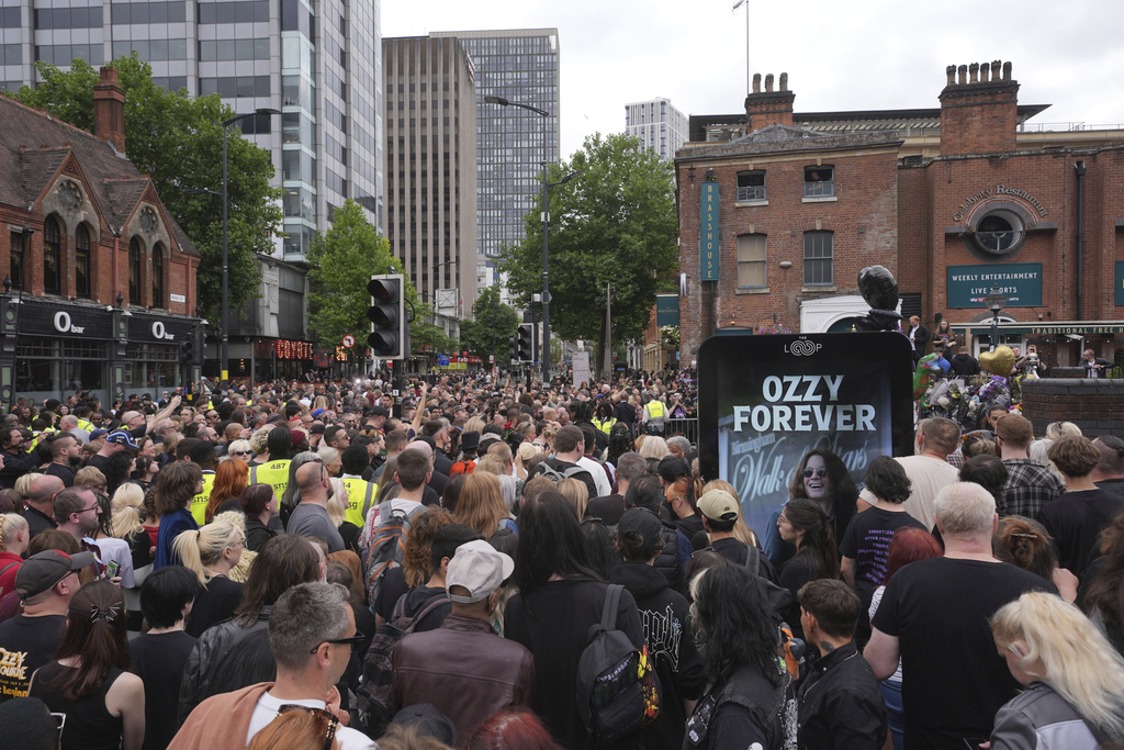 Fans gather near to the Black Sabbath Bridge bench on Broad Street in memory of Black Sabbath frontman Ozzy Osbourne, during his funeral procession, in Birmingham, England.