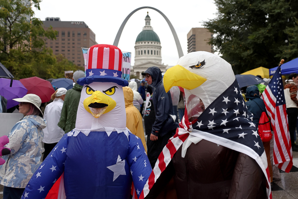Demonstrators wearing inflatable bald eagle costumes gather in Kiener Plaza during the "No Kings" protest in St. Louis, with the Gateway Arch in the background, on Saturday, Oct. 18, 2025.