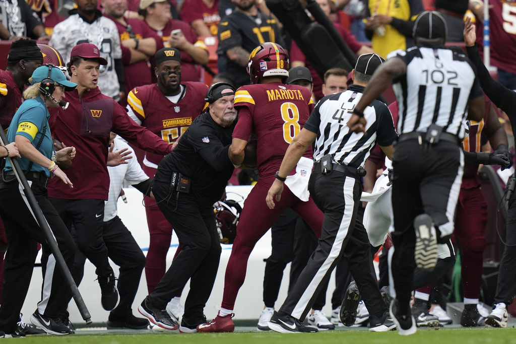 Washington Commanders Dan Quinn is run into on the sideline during the first half of NFL football game against the Las Vegas Raiders, Sunday, Sept. 21, 2025, in Landover, Md.
